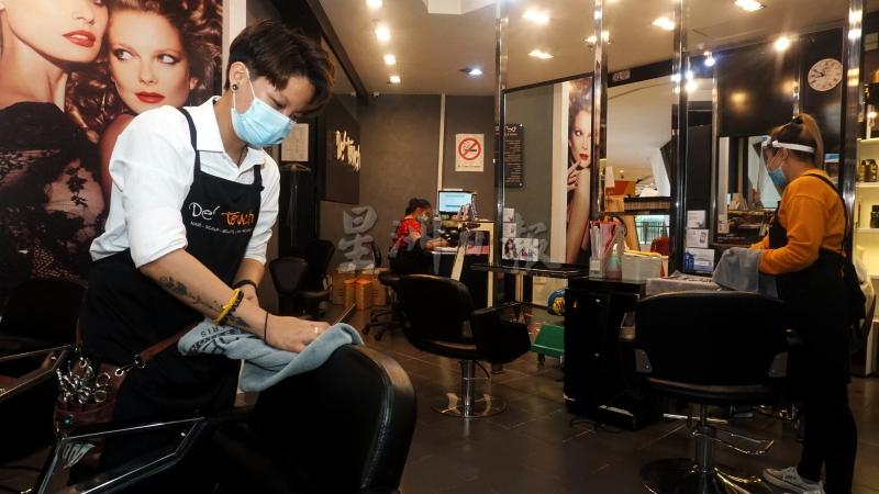 美发师们为顾客理发后，拭抹座椅进行消毒，遵守营业的标准作业程序。  