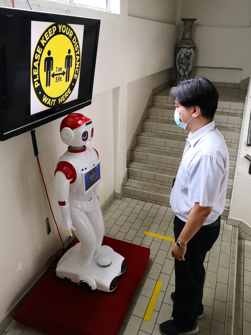 华仁中学教师使用“曼迪测温机器人”测量体温。