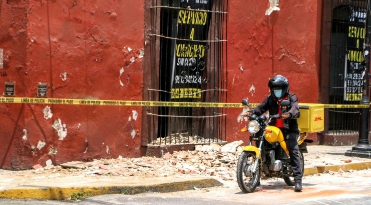 A motorcyclist rides past a damaged building after a quake in Oaxaca. AFP