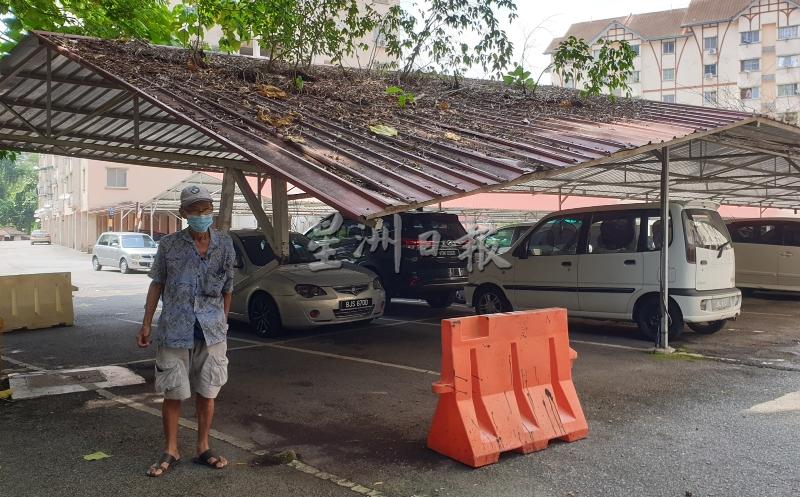 彭亚财向记者展示遭人撞断铁柱，导致车棚屋顶“半倒塌”，但住户却不愿维修。