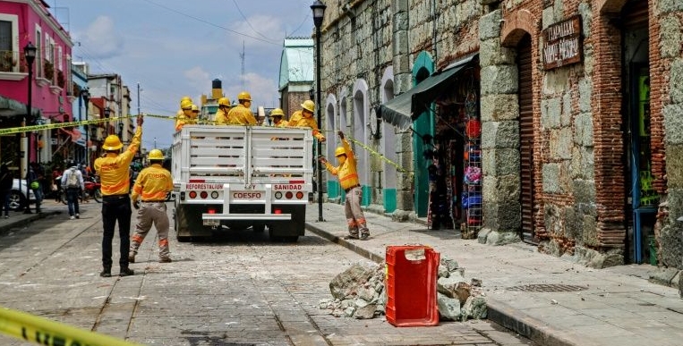 Workers remove rubble and place security tape alerting of a damaged building after a quake in Oaxaca. AFP