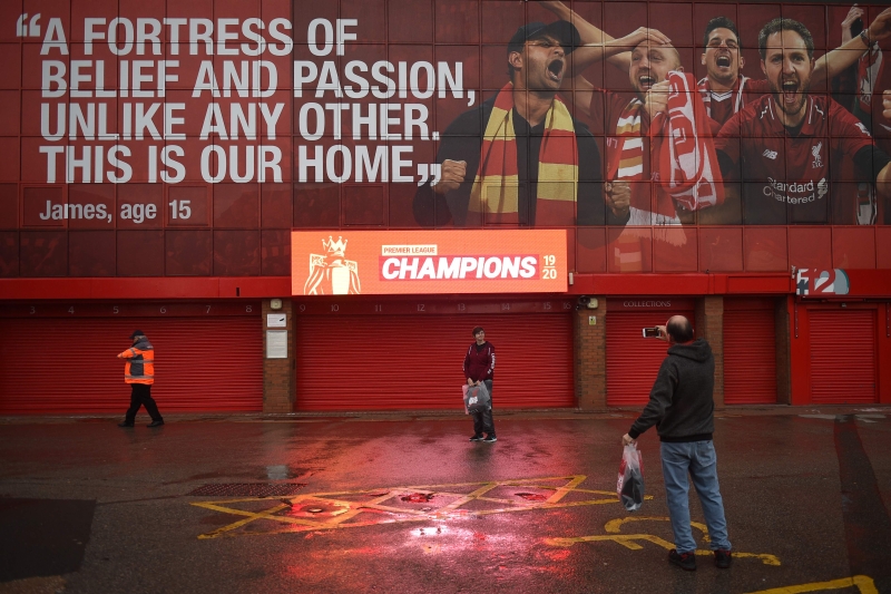 一名利物浦球迷在安菲尔德体育场外新竖立庆祝利物浦赢得英超冠军的的标志下拍照。（法新社照片）