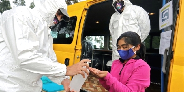 11-year-old Katalina Zuniga is given hand sanitizer before entering her class in a van. AFP