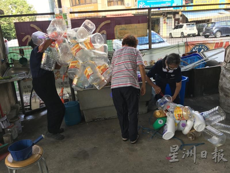 志工为大瓶装的塑料桶绑上绳子，方便回收厂载走。（图：星洲日报）
