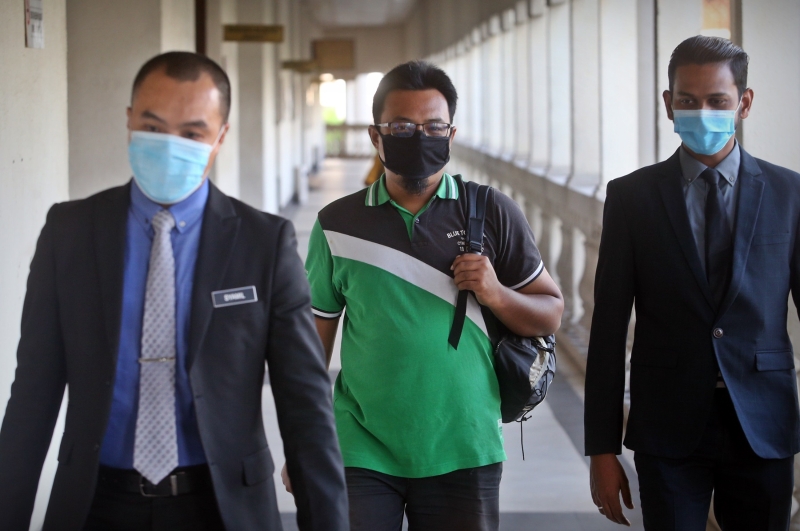 慕纳威（中）于周一早上被反贪会官员带往吉隆坡地庭面控。