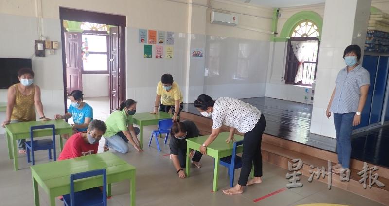 黄清吟（右）视察老师们依照社交距离，排置幼儿的桌椅。