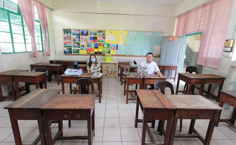 黄天良（右）与教师坐在按照社交距离排好的学生桌椅。