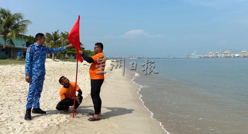 旺赛夫（左起）与队员莫哈末沙苏丁及利查沙将代表“非常危险”的红旗 ，插在北海清洁海滨的沙滩上。