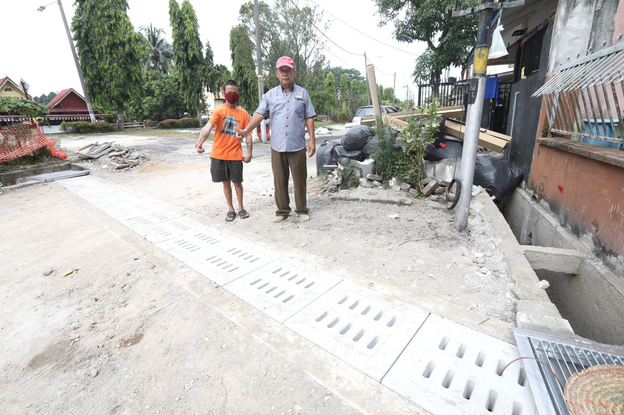 黎丁财（右）今日巡视接近竣工的甲洞乌鲁新村1路的沟渠提升工作。