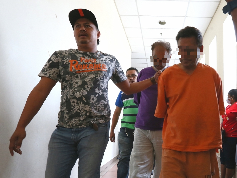 分别身穿紫色和橙色扣留服的拿督主嫌和律师嫌犯抵达法庭时，低头躲避媒体镜头。