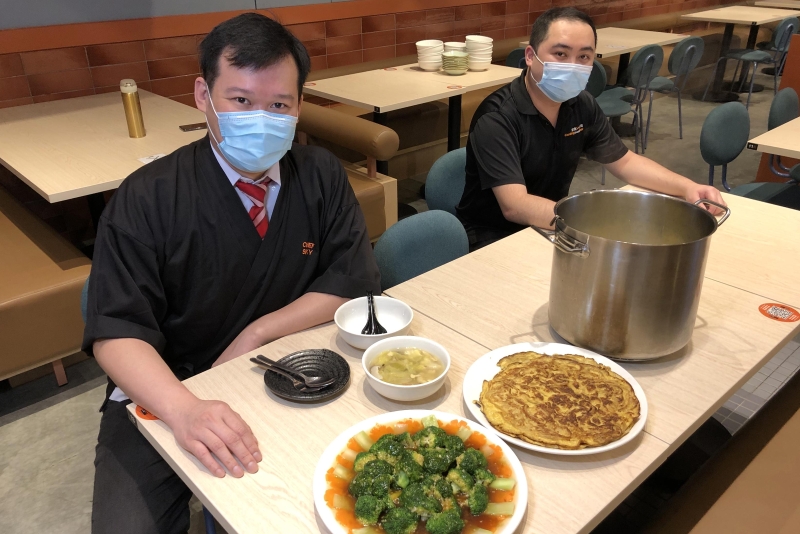戴思凯（左）和张文嘉煮了一桌简单但充满家乡味的菜肴。（照片取自《海峡时报》）