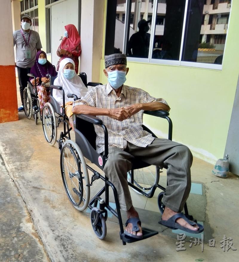 仄依布拉欣（右起）及蓝拉坐着轮椅，在投票站外等候进入投票。