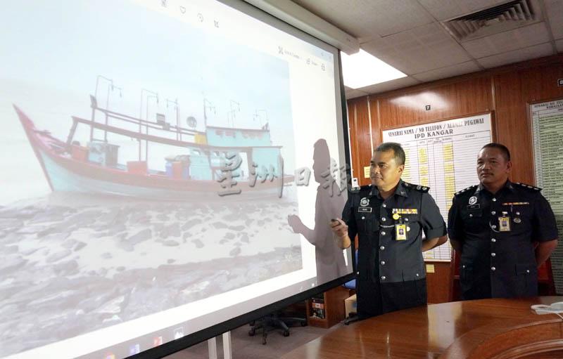 华礼秋（左）在加央警区刑事罪案调查组主任慕萨陪同，向媒体展示拦截的渔船。