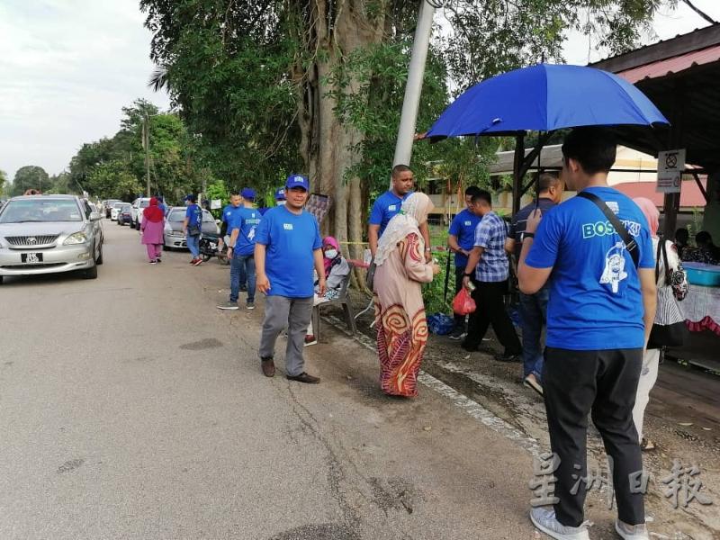 一群身穿印有"BOSSKU"字眼的蓝色T-恤支持者。