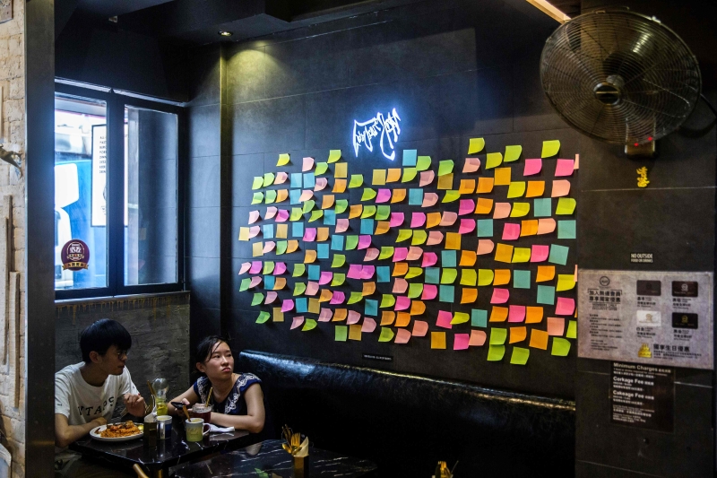 港府发表声明，指「光复香港　时代革命」口号有港独意味。声明一出，社交媒体纷纷出现「打擦边球」的八字创作，例如「康复香港 时代拼命」、「_ _ _ _，_ _ _ _」，或用英文「GFHK」表达「光复香港」；亦有人举起白纸代替文宣。连侬墙上的贴纸也留空白，作无声抗议。(图：法新社)