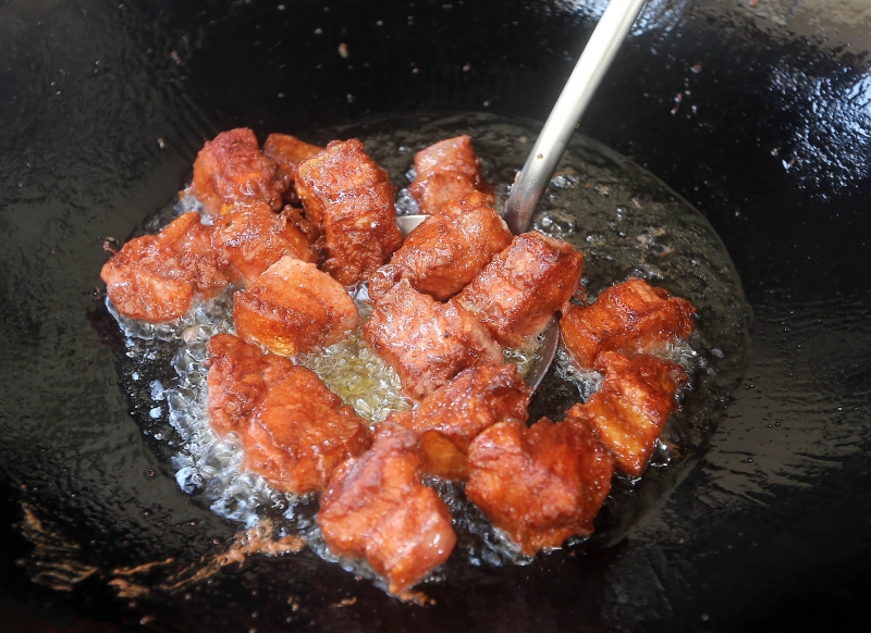 3.把腌制好的五花肉倒入热锅中，炸至金黄色。