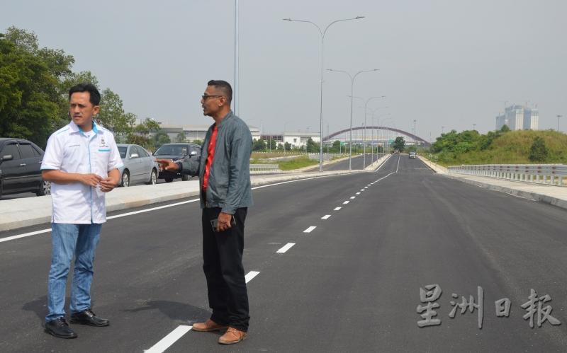吴俊益（左）与槟州发展机构官员伊扎巡视即将通车的新路。（图：星洲日报）