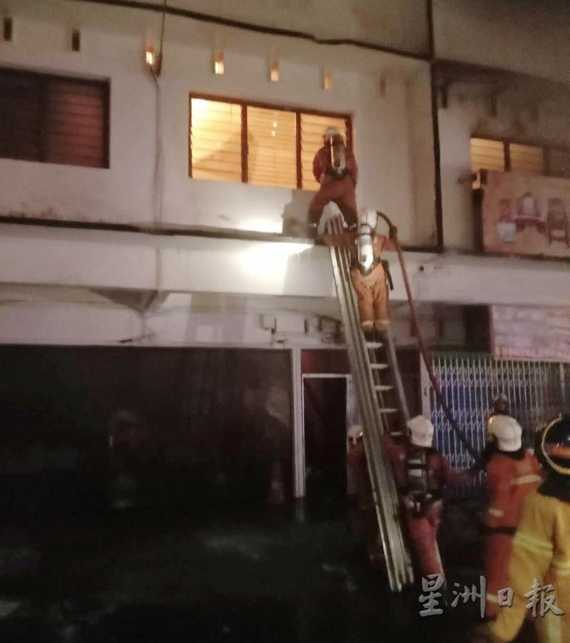 大火在店屋楼上内部燃烧，消拯员使用爬梯射水灭火。
