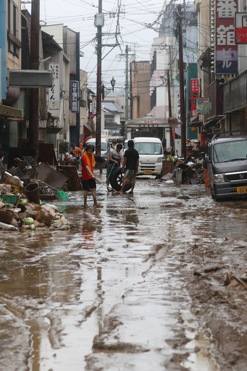 当地的居民在努力清理洪水后淤泥遍布的街道 。(法新社照片)