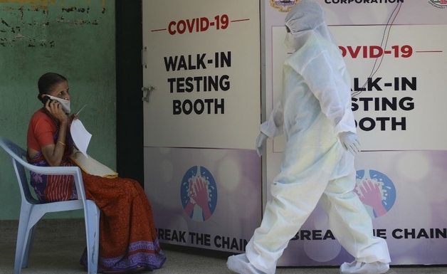 A medical technician walks past a woman waiting for COVID-19 test in Chennai. AFP