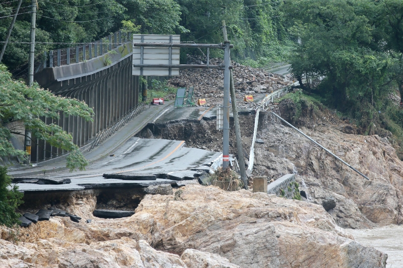 熊本县芦北町近球磨川的一条公路在暴雨洪水下被冲断。当地许多地区仍因桥断路裂，断水断电，呈孤立状态。（法新社照片）