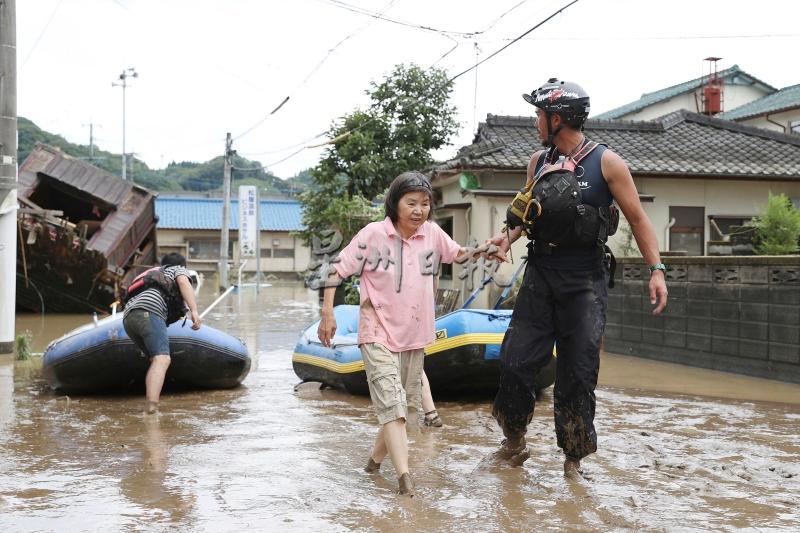 在救援人员扶持下，一名受困妇人涉水撤离。（美联社照片）