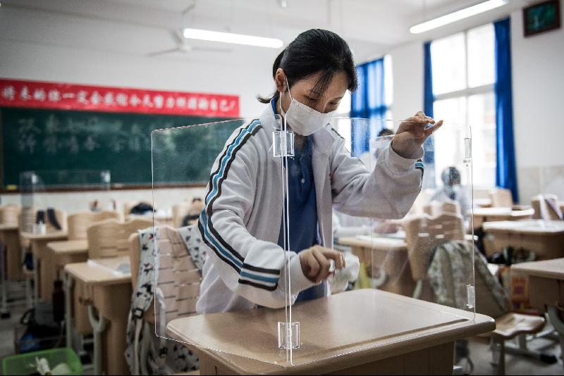 因疫情而展延的中国高考周二登场，各地纷纷出台防措施。图为在湖北省武汉一所学校，一名学生清洁桌位上的隔板。（图：法新社）