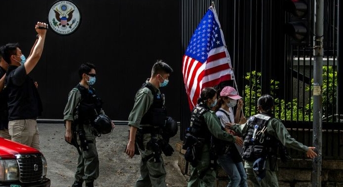 Police remove a woman holding a US flag outside the US consulate in Hong Kong. AFP