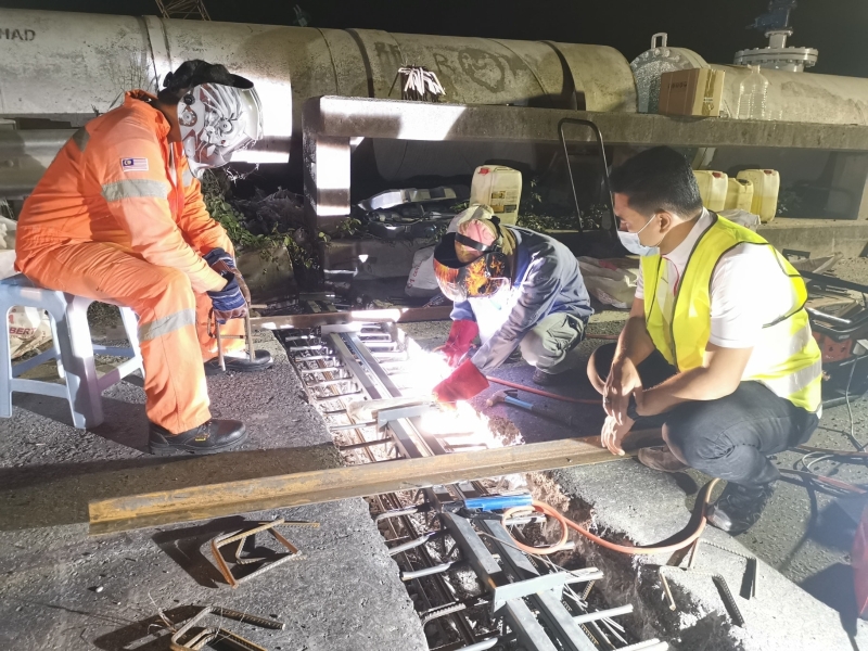 阿兹米占（右）视察施工人员，漏夜对裂缝日益扩大的桥梁接口处，进行维修与烧焊工作。