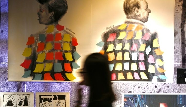 A woman walks past a painting at an exhibition about Hong Kong's protests in Taipei. AFP