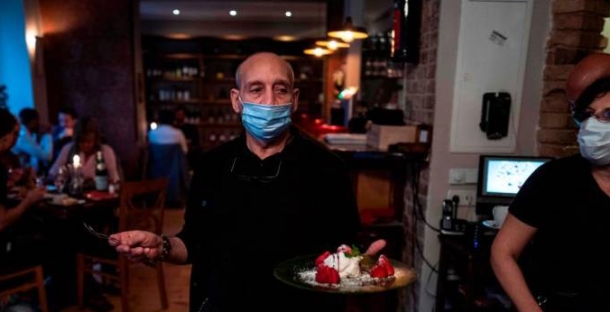 A waiter wearing a face mask serves dessert at Pepenero, an Italian restaurant in Berlin's Prenzlauer Berg district. AFP