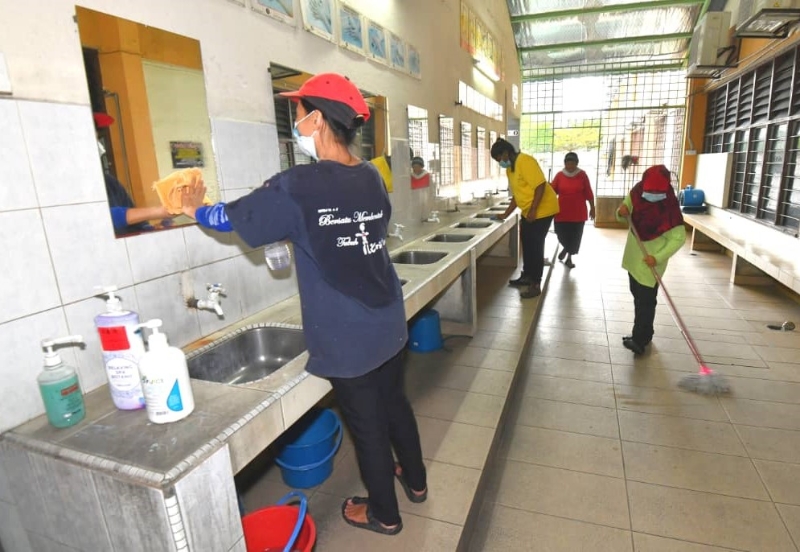 校工忙于清洁消毒校园，让学生在卫生环境下回到校园生活。