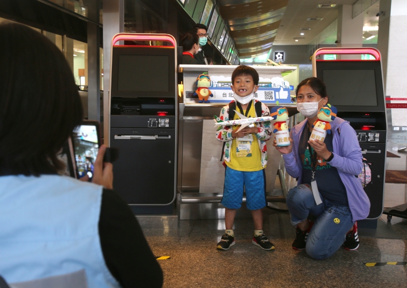 小朋友开心的拿著机场纪念品与妈妈拍照留念。