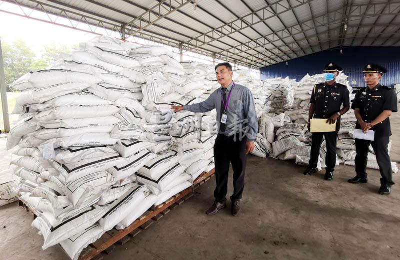 雷蒙（左）展示吉州贸消局起获的12万2060公斤，总值13万3760令吉的津贴肥料。