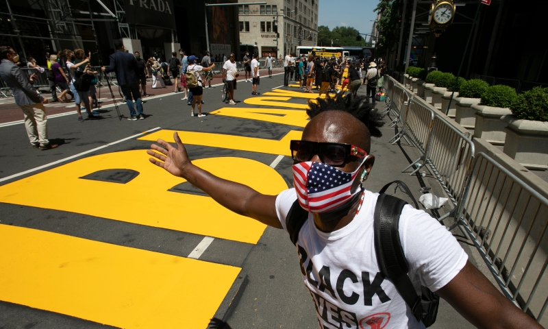 戴著美国国旗图案口罩的非裔民众兴奋地与刚漆上的字体合影。(图：美联社）