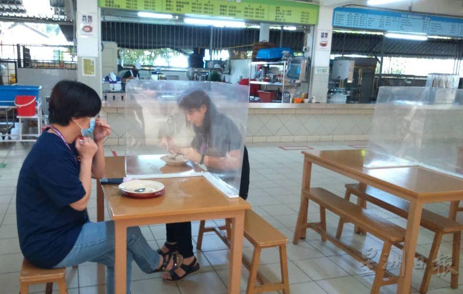 培中食堂餐桌装置透明塑料片，将用餐者相隔离。

