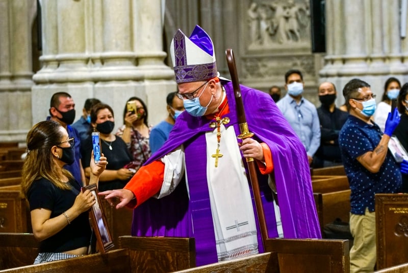 在儀式上紐約大主教蒂莫西·多蘭為逝者的照片獻上祝福。 （圖：美聯社）