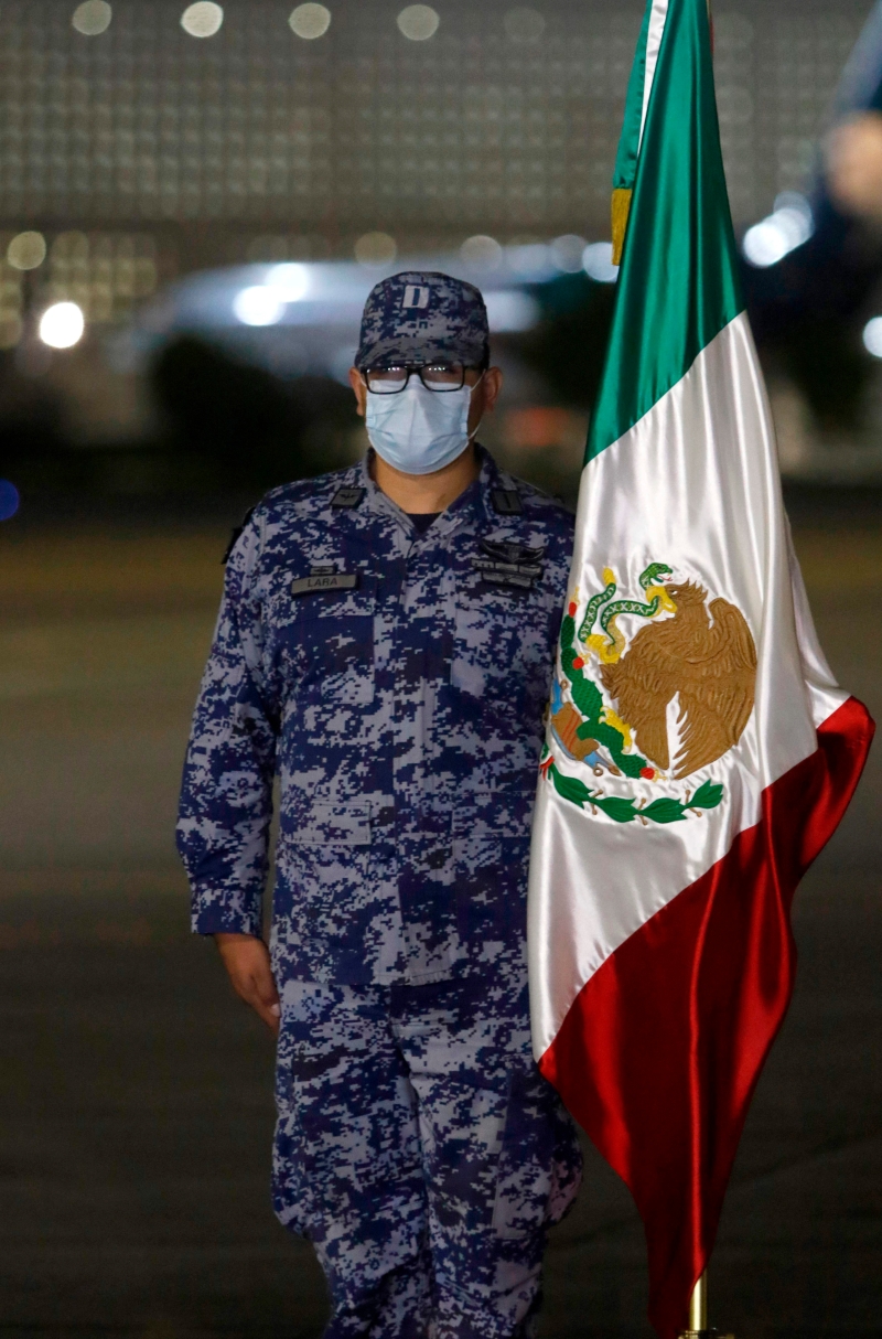 在墨西哥城機場舉行的歸國儀式上，武裝部隊成員手持國旗迎接回國的逝者骨灰。 （圖：法新社）