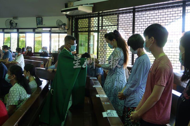 教友们从天主教诗巫教区副主教李福财（左）手中领过圣体。
