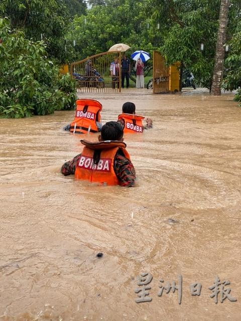 甘榜本班水位极深，消拯人员身穿救生衣涉水而过，走向“岸边”等待救援的灾黎。