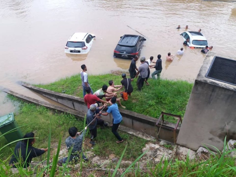 瓜拉大汉河水高涨·数辆轿车泡在水中，热心民众使用绳索将车子拉上岸，但不成功。