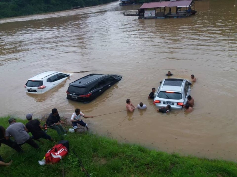 瓜拉大汉河水高涨·数辆轿车泡在水中，数名村民下水尝试将泡在水中的车子推上岸。