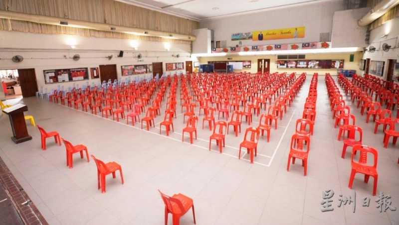 三德华中下午班的学生在等候进入教室前，将被分为两批坐在篮球场和礼堂准备的塑料椅。