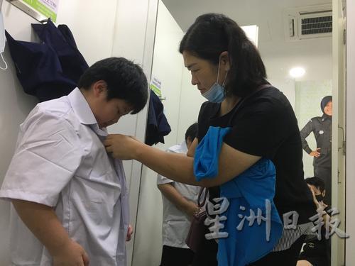 吴凭恩(左)在假期变得更可爱了,原来28号的校服已经穿不下,妈妈陈丽婷(右)赶快带他来买新校衣校裤。