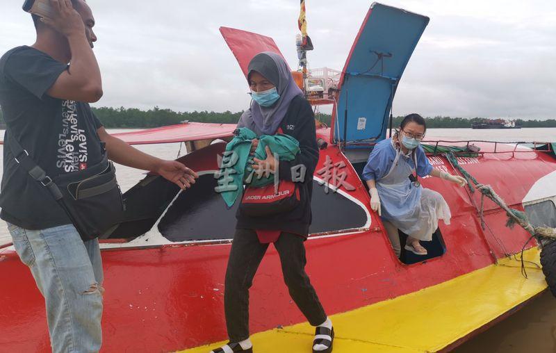 协助接生的女乘客抱着女婴走下快艇。

