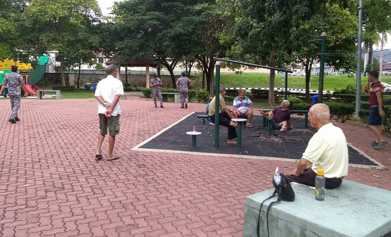 一群老人在马口公园里做运动后，休息聊天，由于都有保持社交距离，因此执法人员出现都没有恐惧。
