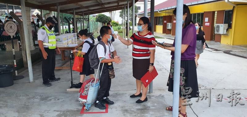 丹A新村的学生根据标准作业程序，排队使用消毒搓手液及测量体温。