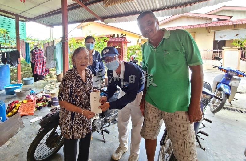 在丹A村委的见证下，慈济志工沈耀伟（中）把慰问金交给年老的灾民。