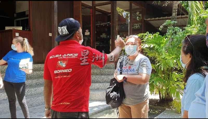 仙本那旅游业者根据标准作业程序为到访者测量体温。