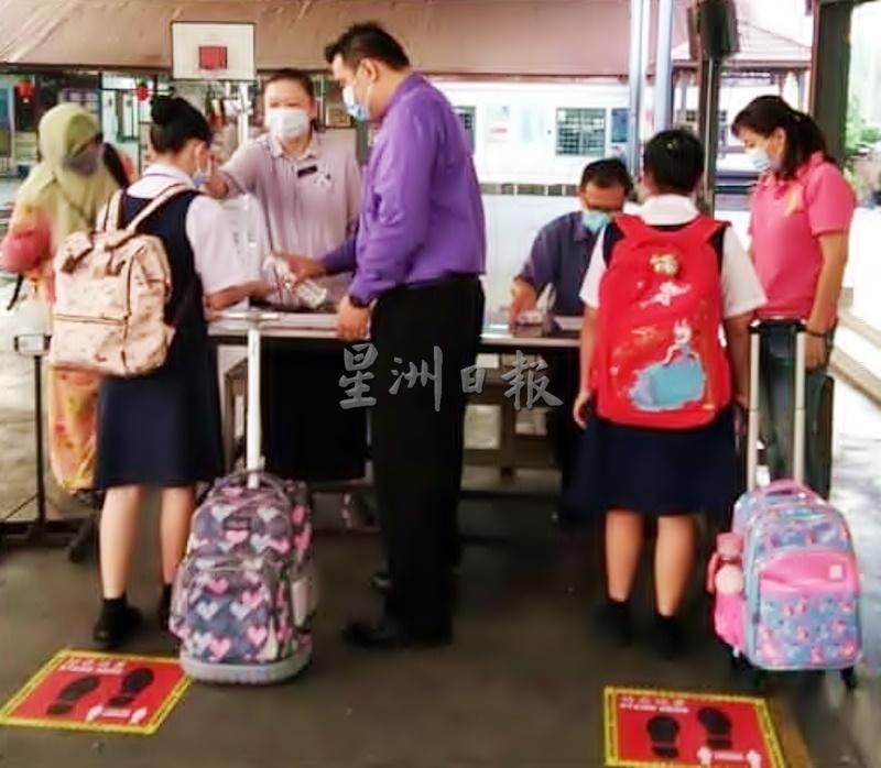 蔡鸿盛(前左二)观察学生复课进入学校前所进行的的安全措施。